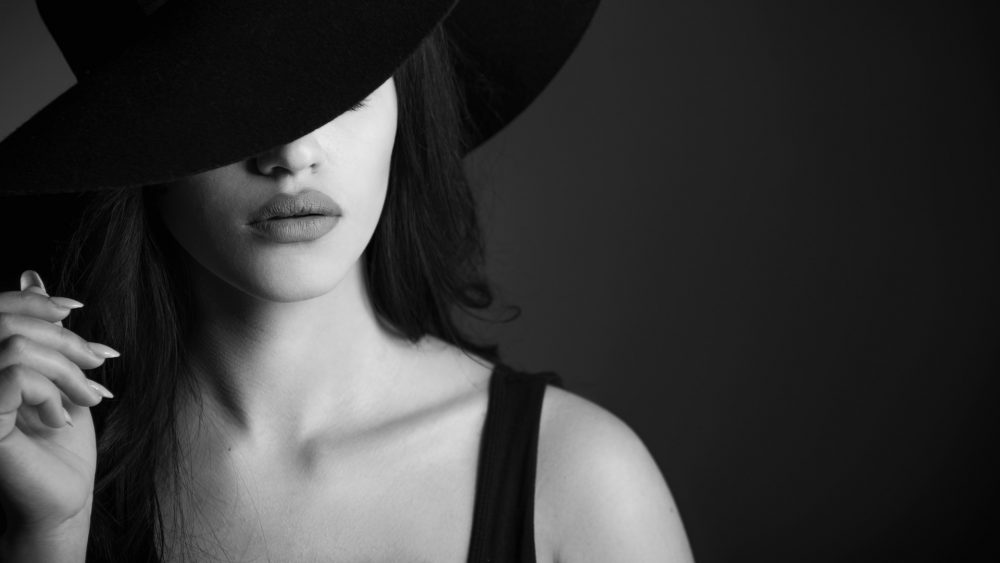 Black & White Photo with Model Heileen Arias and Brandon Marsh Photography Dramatic Moody lighting focused on lips & holding hat fashion portrait