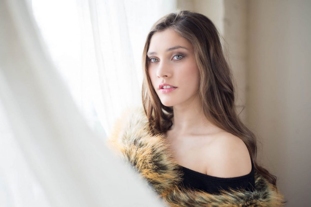 Soft Fashion & Beauty Portrait of Model in front of window with fur blanket photographed and edited By Brandon Marsh Photography